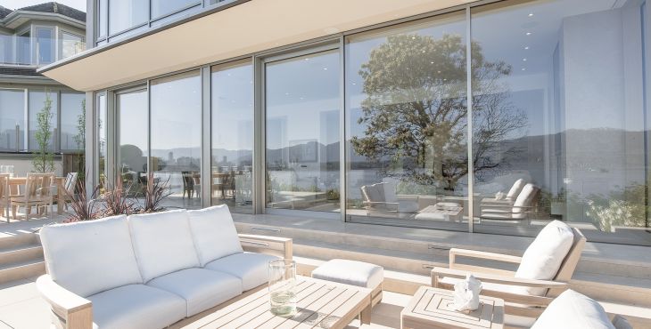 Blick von sonniger Terrasse auf großformatige UNILUX Holz-Alu Hebe-Schiebe Anlage