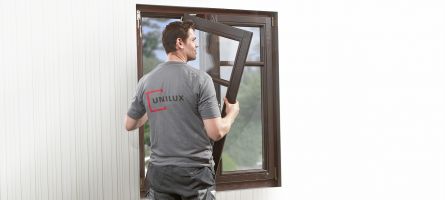 UNILUX-Mitarbeiter montiert Holzfensterflügel