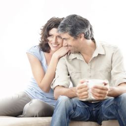 Mann mit Kaffeetasse sitzt mit Frau auf Couch