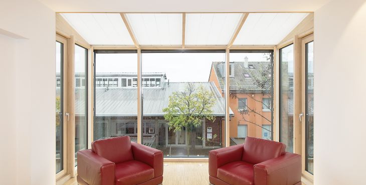 Wimnertgarten oder Balkon mit Balkontüren aus Holz in hellem Wohnbereich mit großen Holzfenstern