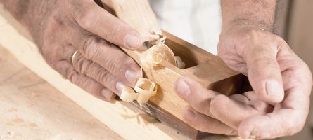 Schreiner bearbeitet Holzrahmen mit Hobel