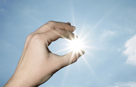Hand hält Sonne zwischen Fingern Symbolbild